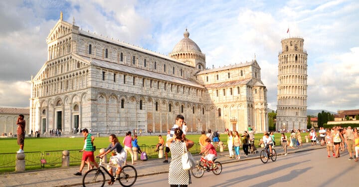 Pisa, Italy - August 25, 2013: Tourists on Square of Miracles visiting Leaning Tower in Pisa, Italy. Leaning Tower of Pisa is campanile and is one of the most famous buildings in the world